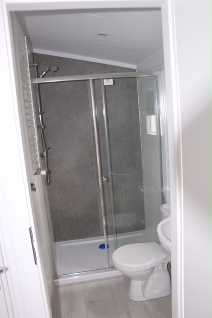 Das Badezimmer ist exklusiv eingerichtet. Die Dusche ist 1,10m x 0,85m mit einem flachen Einstieg. Die Heizung dient als Handtuchhalter. Unter dem Waschbecken befindet sich ein kleiner Schrank.

